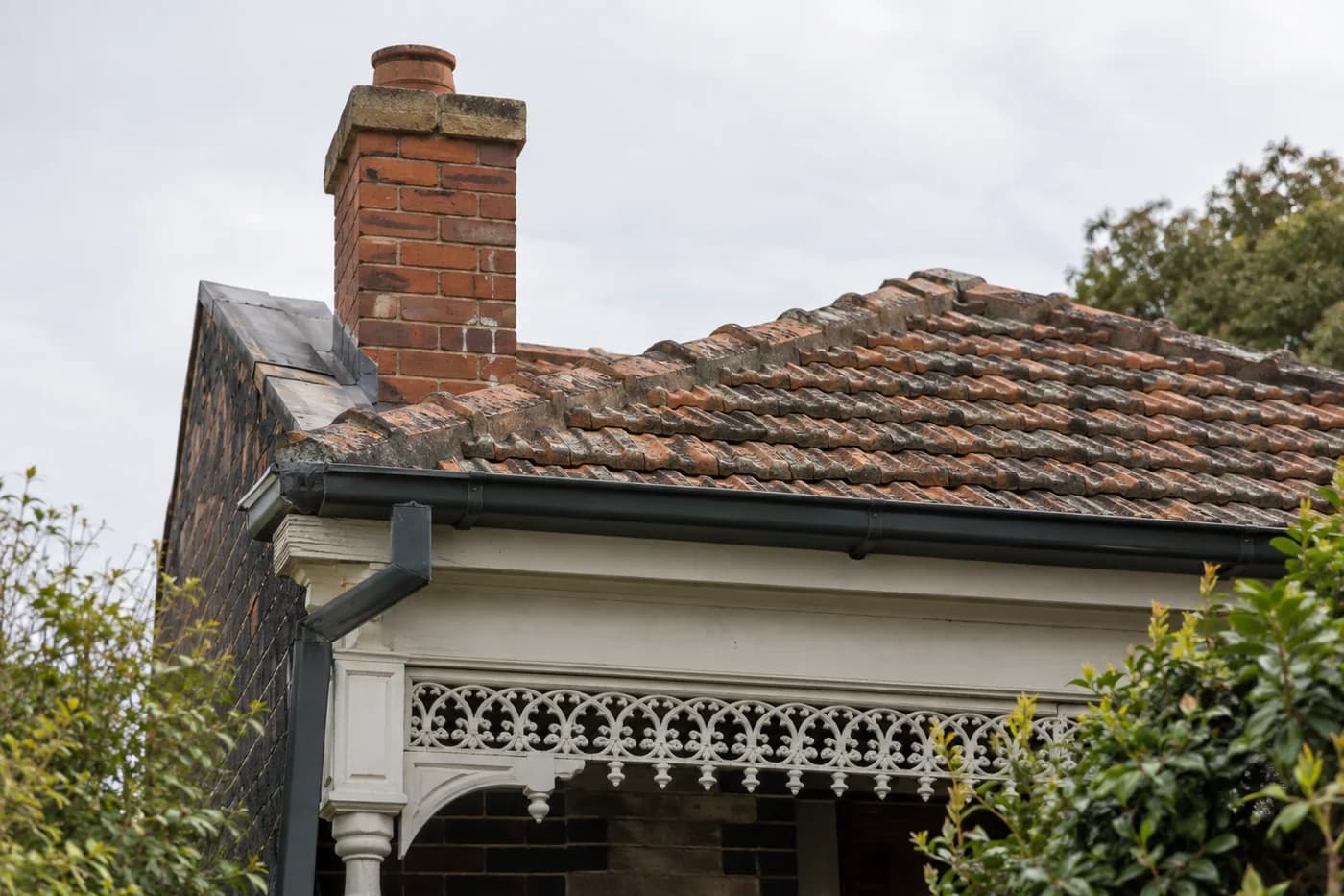Weathered terracotta roof tiles, brick chimney and gutter on a Victorian terrace